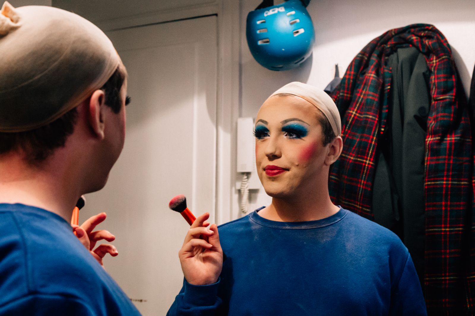 Man with makeup looks into the mirror