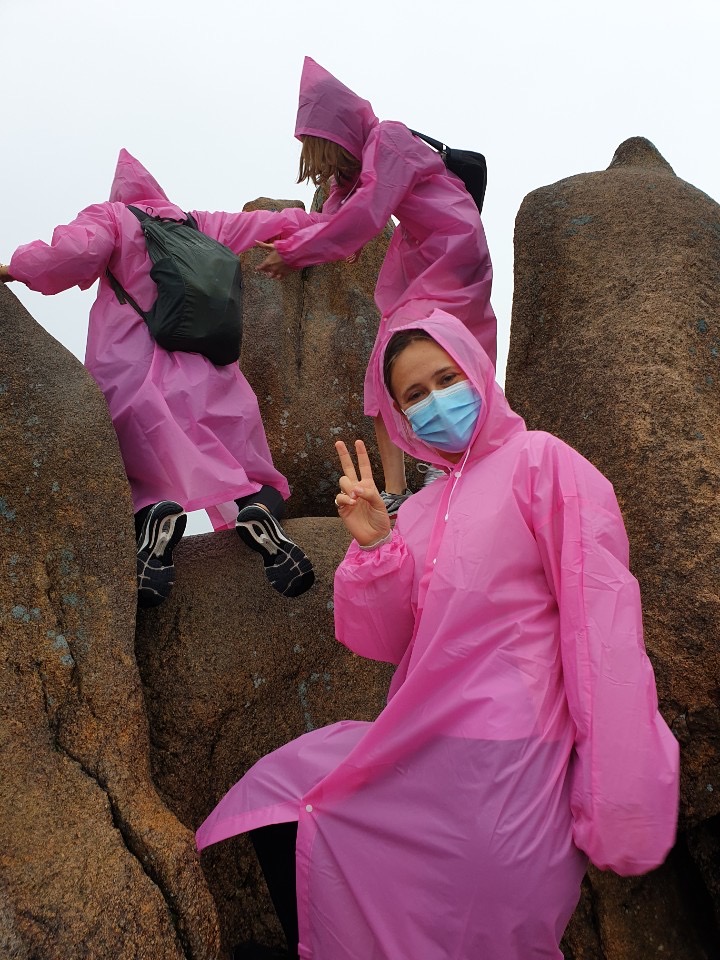 Student with a mask wearing a pink rain coat and