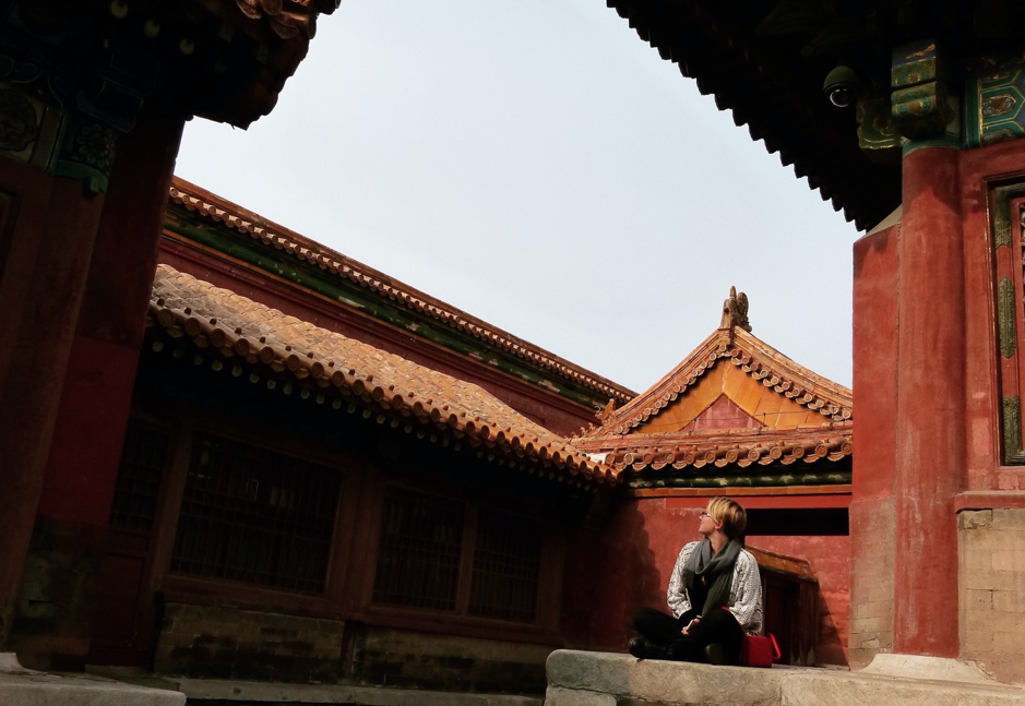 young woman sitting by old house in China