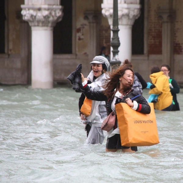 Tourists walking through flood in Venice