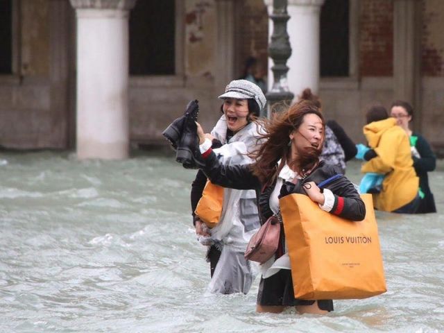 Tourists walking through flood in Venice