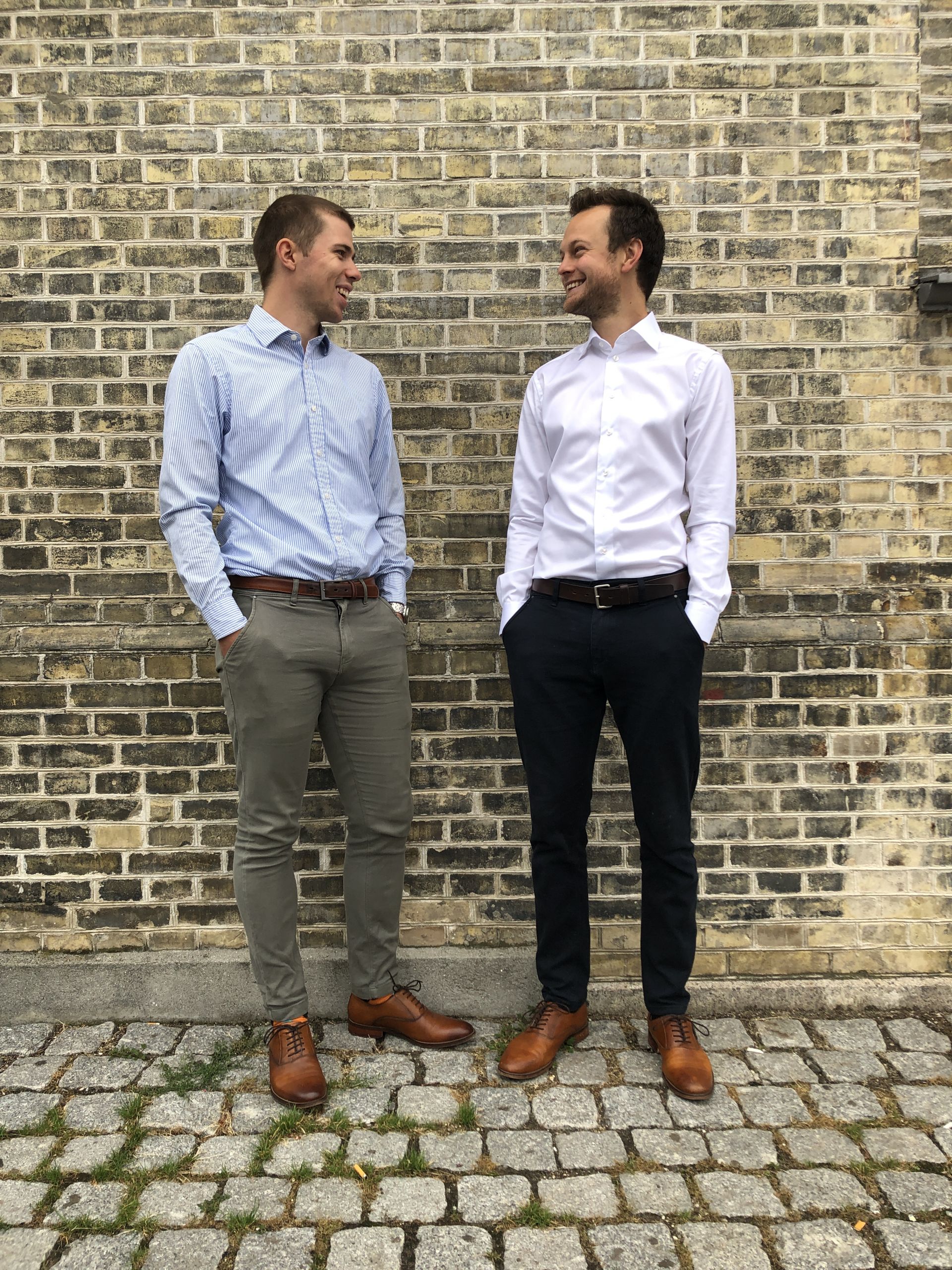 Two men in suits standing up against a wall