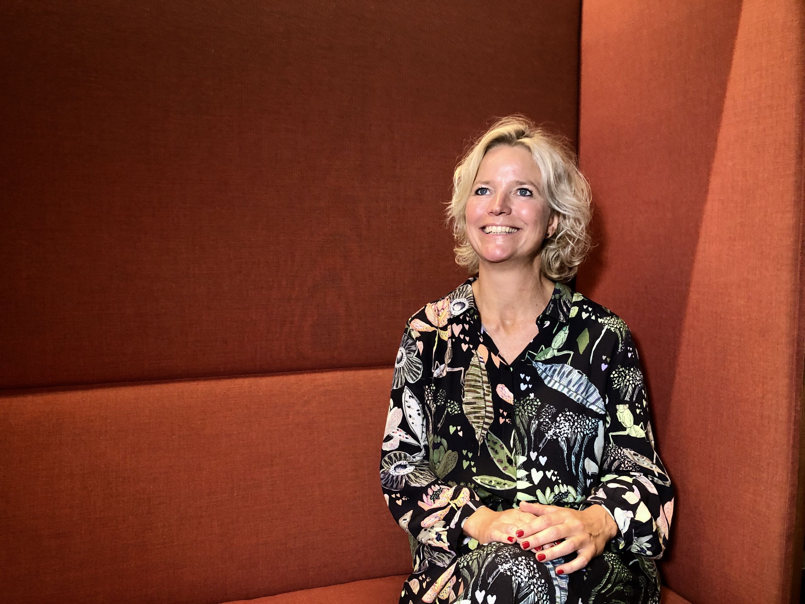 Woman in flower dress sitting in a red couch