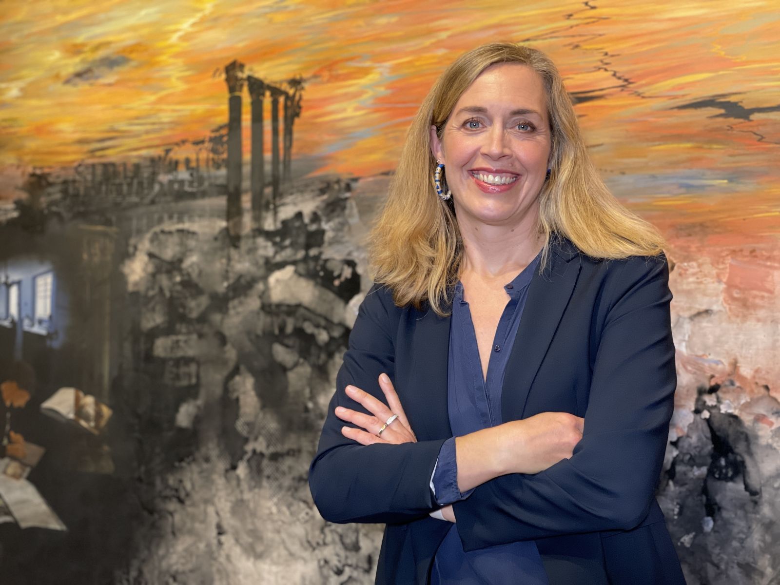 Woman in blue shirt standing in front of painting