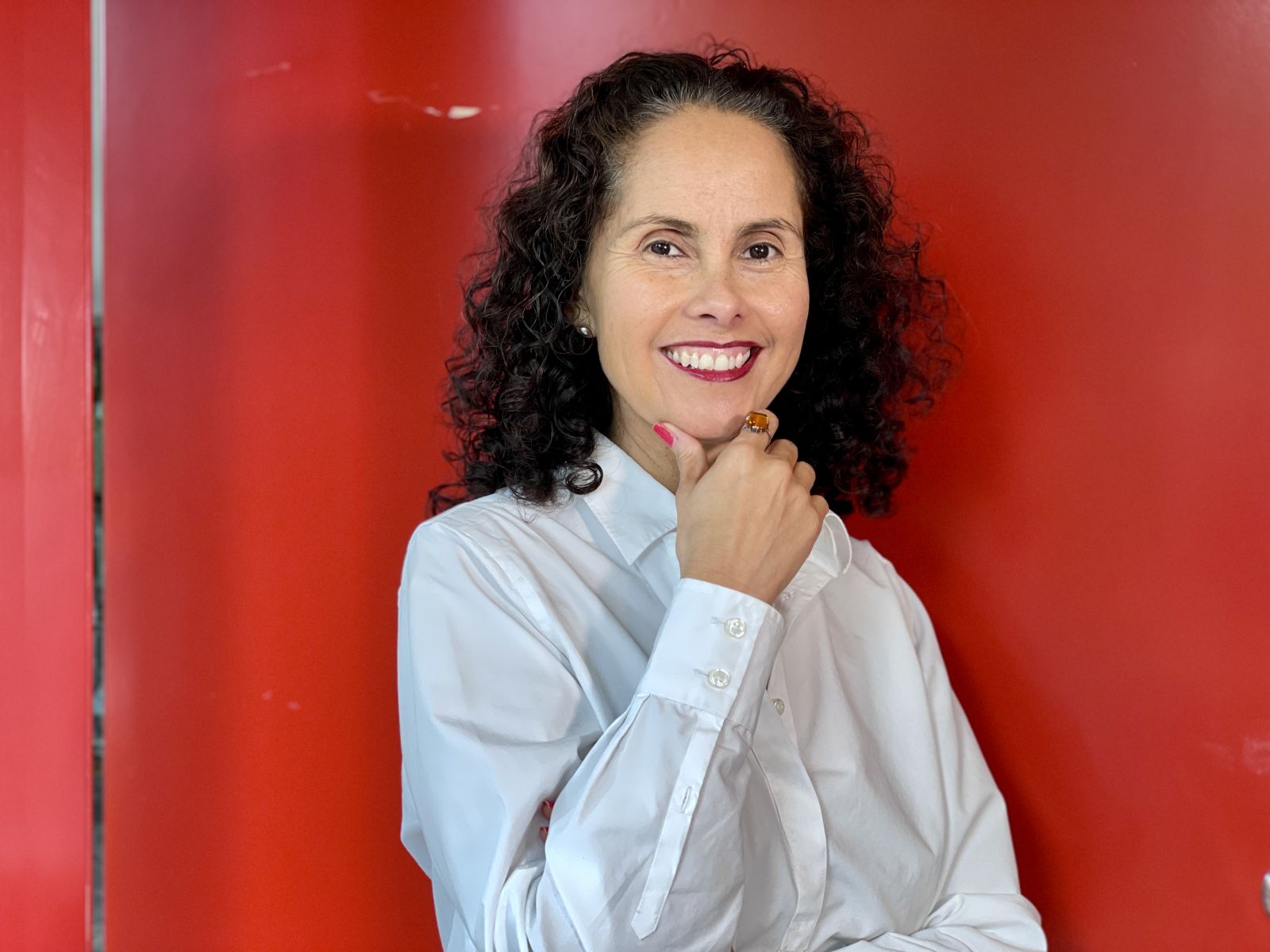 Woman with brown, curly hair in front of red door