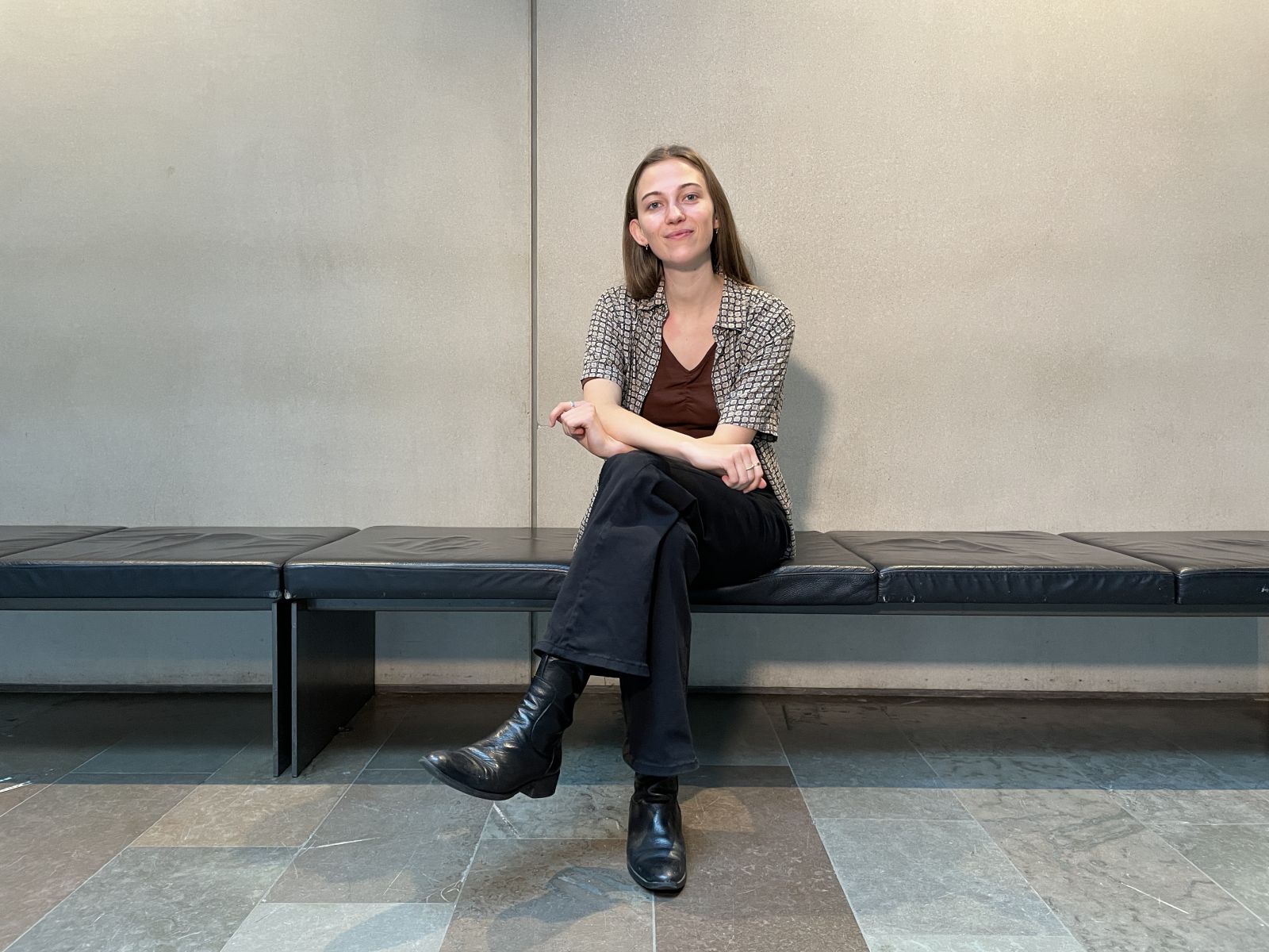 Woman sitting with crossed legs on a black leather bench